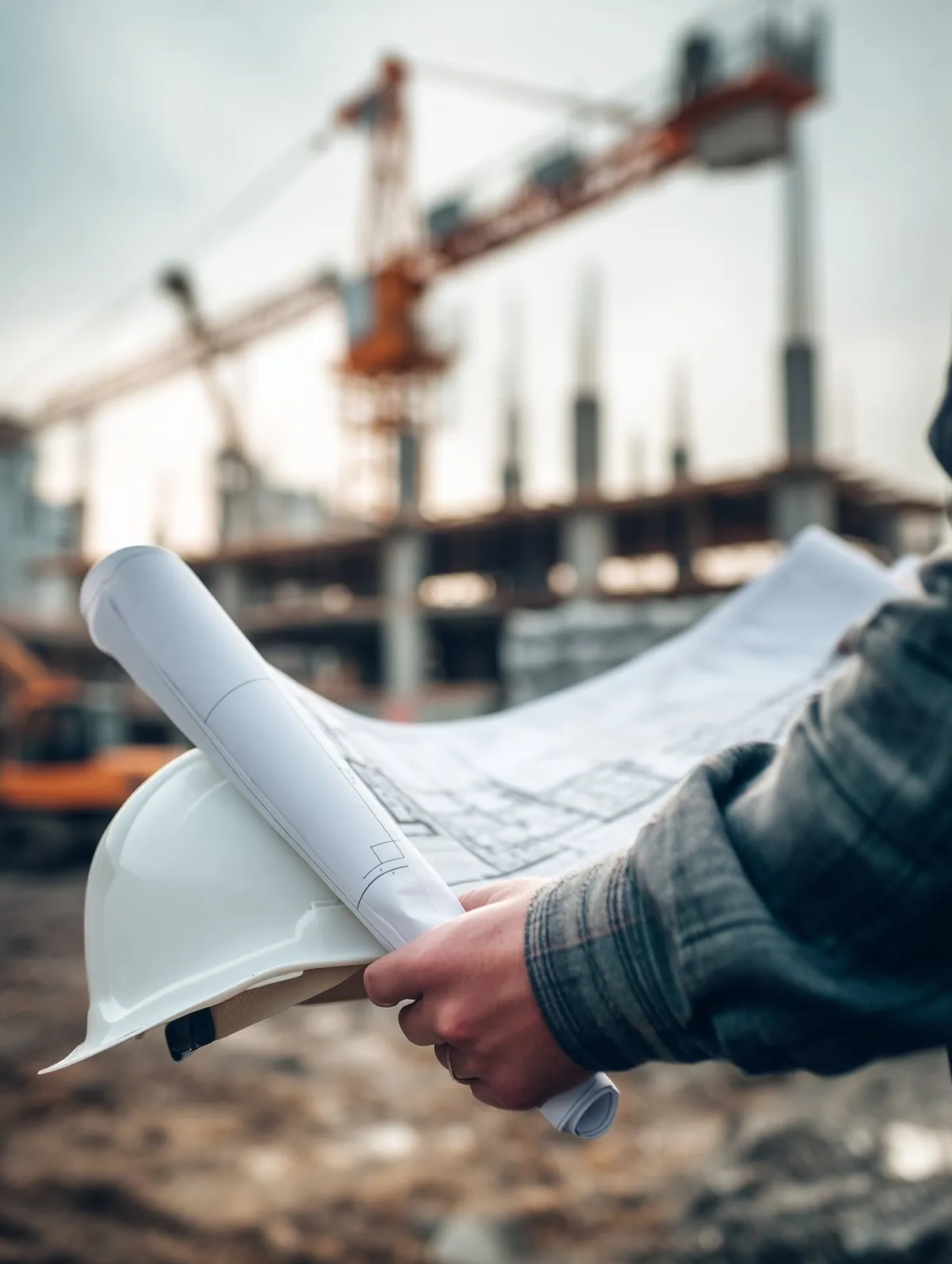 Plans et casque de chantier devant un bâtiment en construction